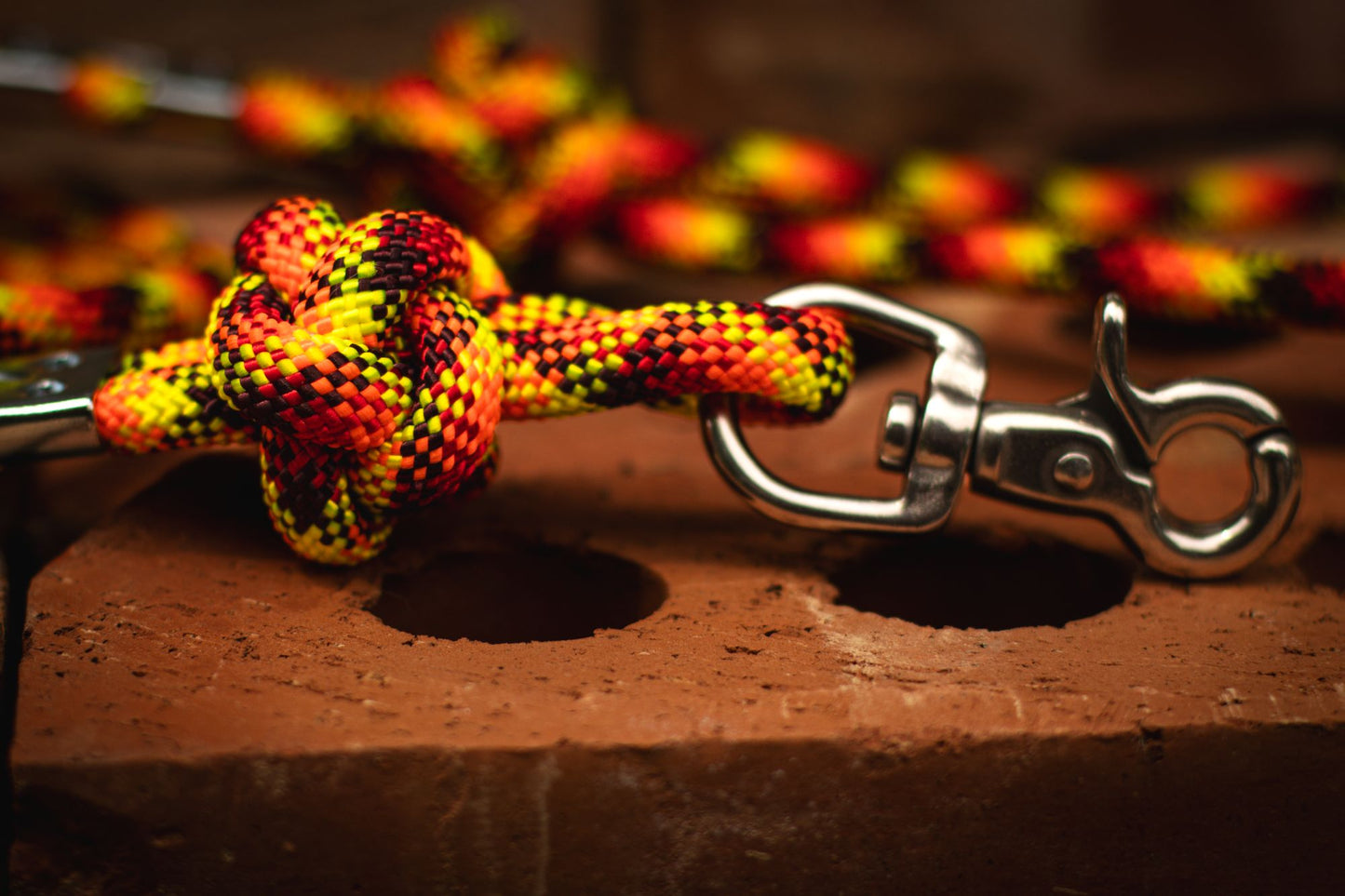 Close-up of a colorful rope knot with a metal clip on a wooden surface