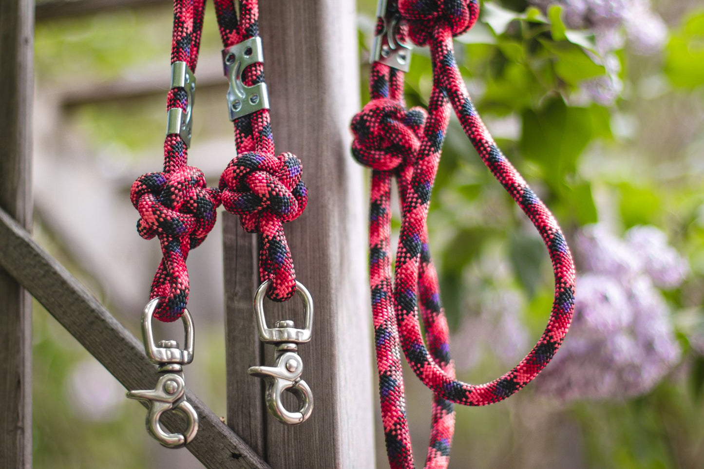 Red and black braided dog leashes with metal clips on a wooden background