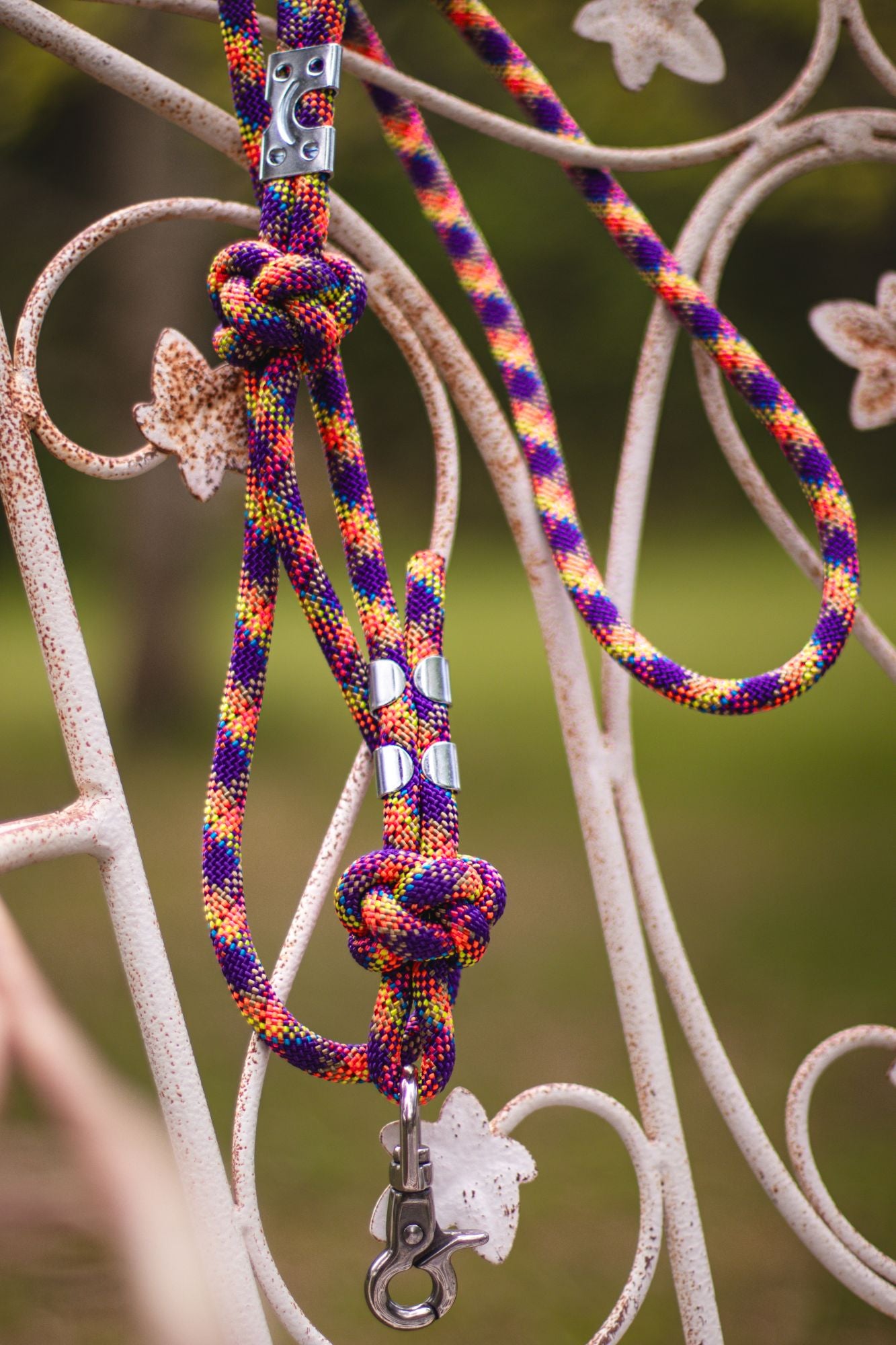 Colorful braided dog leash with metal clips on a decorative metal surface.