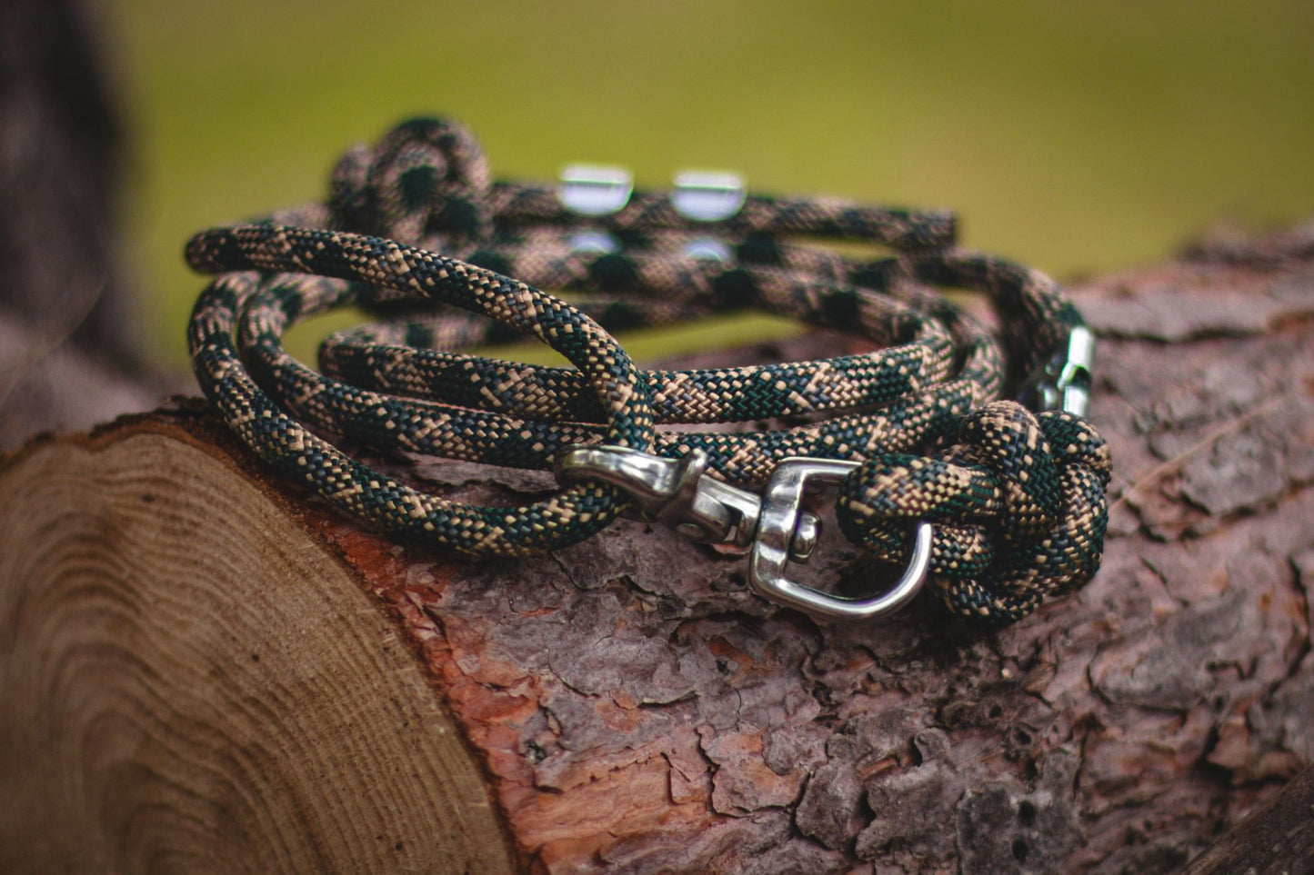 Branded dog leash on a wooden log with a blurred green background