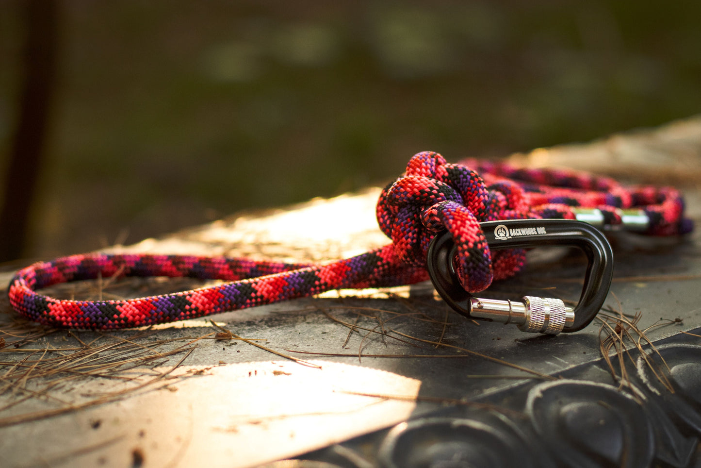 Red and black braided rope with a knot and carabiner on a textured surface
